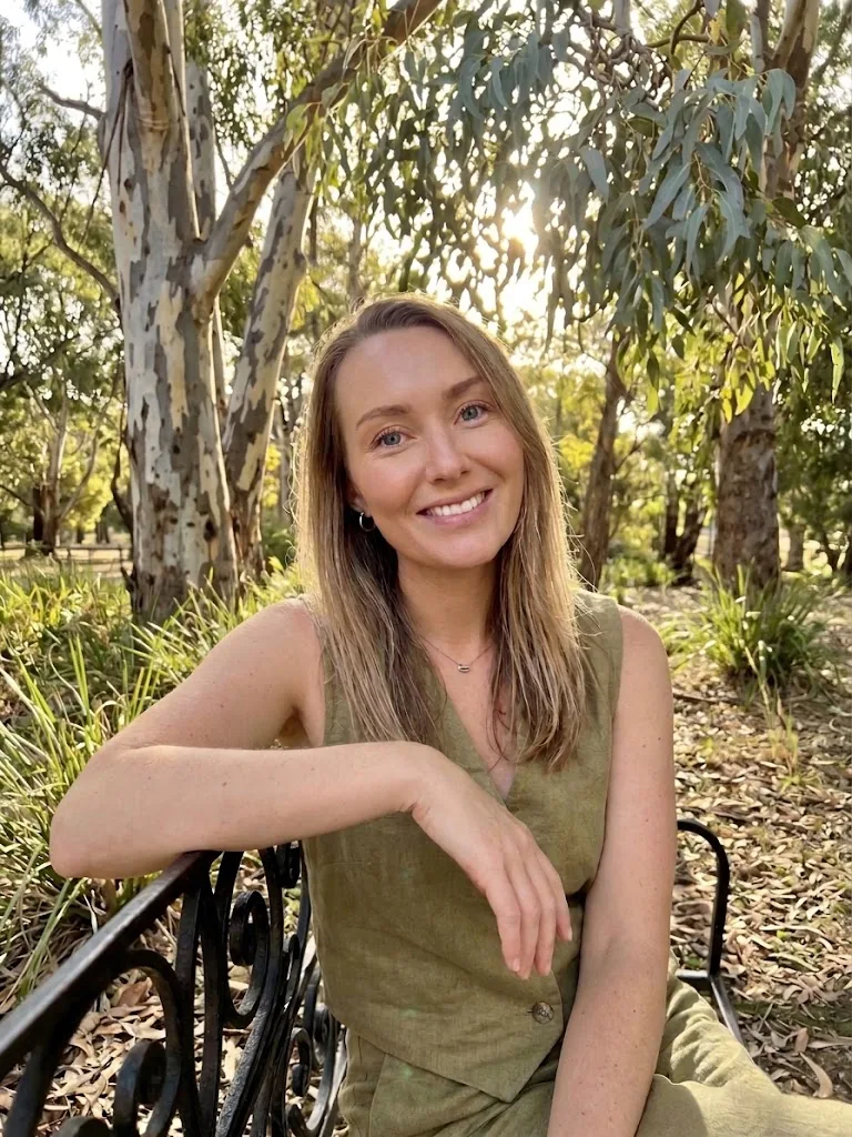 Lisa, founder of Amber Codex, sitting on a garden bench under gum trees in Adelaide